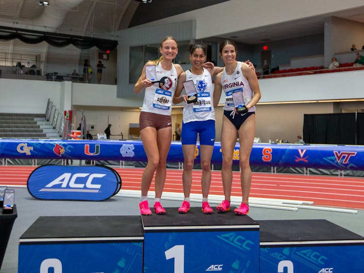 Amina Maatoug (middle) stands on the podium after finishing first in the women's mile at the ACC Championships.