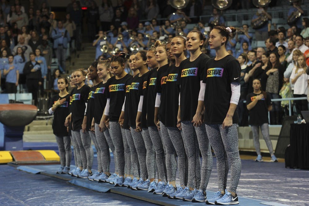 The gymnastics team stands together wearing shirts with the saying “#BeTrue” in honor of the LBGTQ movement before their meet against Florida on Friday.