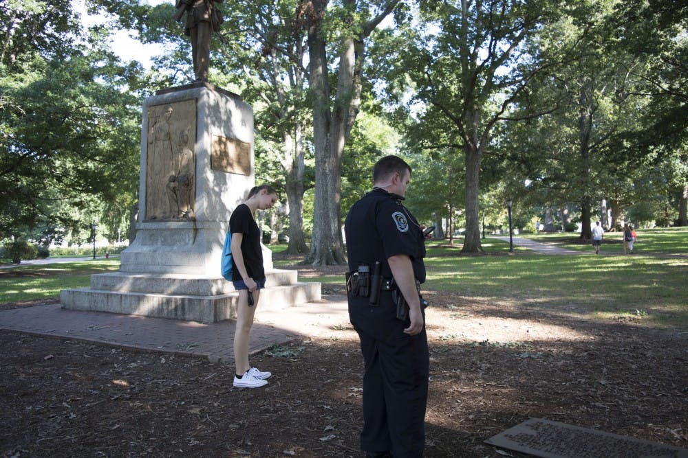 A campus police officer reads a sign that was removed from the Silent Sam statue on UNC's campus, on August 20, 2017.