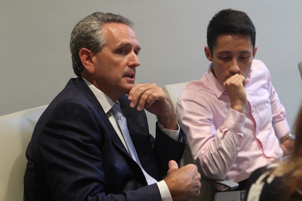 <p>Bubba Cunningham (left), UNC Athletic Director, contributes to discussion at a 2016 meeting of the Faculty Athletics Committee (FAC) while Ezra Baeli-Wang, a student athlete advisory council representative, listens intently.</p>