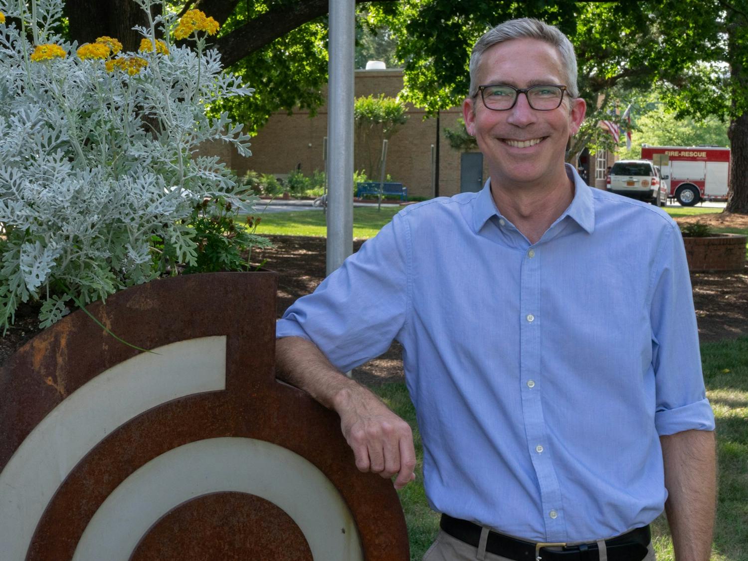 Damon Seils, Carrboro council member, poses beside the Carrboro Town Hall sign on Tuesday, June 8, 2021. Seils announced he is running for Mayor of Carrboro.