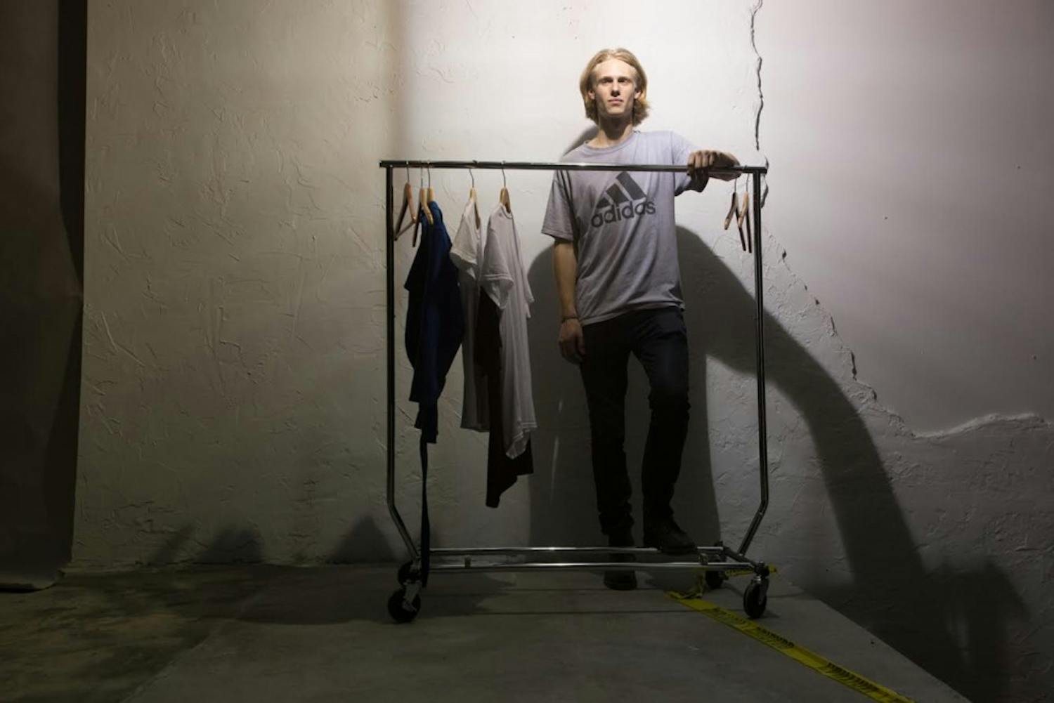 James Creissen, a sophomore business major, poses in front of a rack of clothes he designed. Creissen held a fashion show on East Rosemary Street Thursday night.