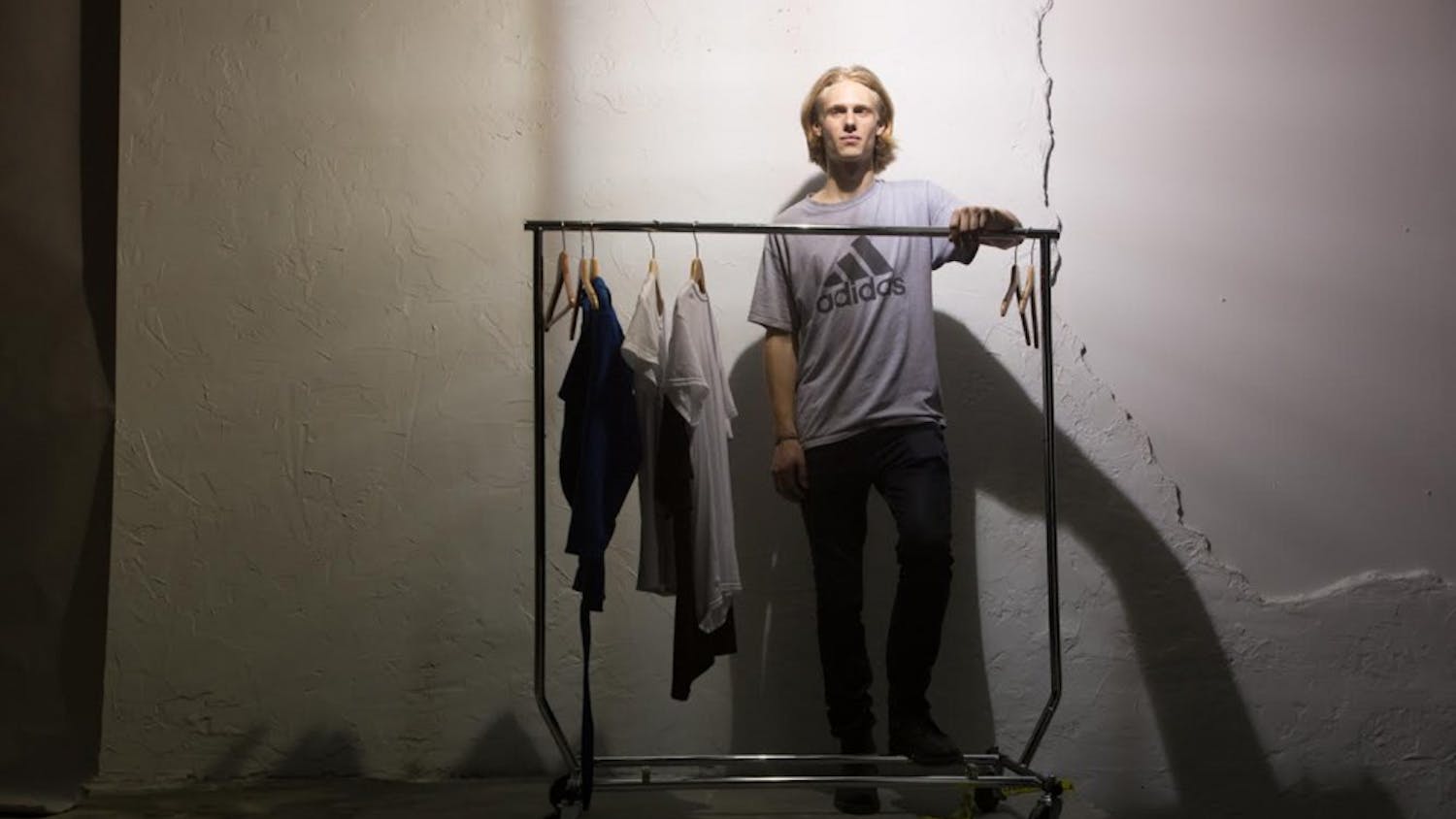 James Creissen, a sophomore business major, poses in front of a rack of clothes he designed. Creissen held a fashion show on East Rosemary Street Thursday night.