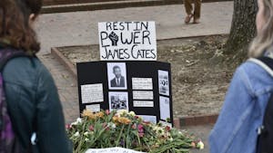 DTH File. Students mourn around a memorial for James Cates in 2018 at the site where he was killed in 1970.
