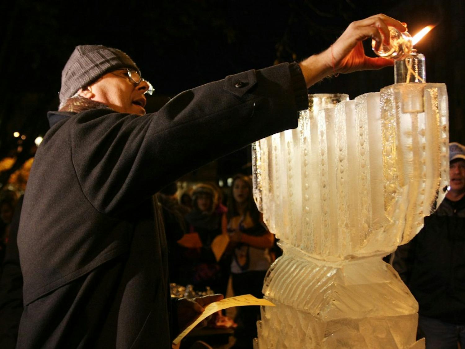 	Hanoch Labowitz of Miami lights the first candle on a giant ice sculpture of a menorah before a large crowd in the Pit on Wednesday evening. Students and community members gathered to celebrate the first day of Hanukkah with members of Chabad of Chapel Hill. Activities included crafts for kids, singing, free food and a live performance by Gmish, a klezmer band.  