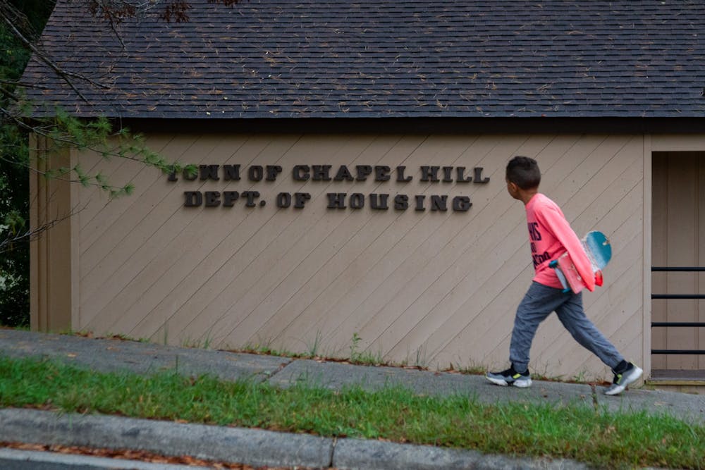 A young boy with a skateboard walks past the Chapel Hill Department of Housing in the Northside neighborhood of Chapel Hill on Sunday, Oct. 25, 2020.