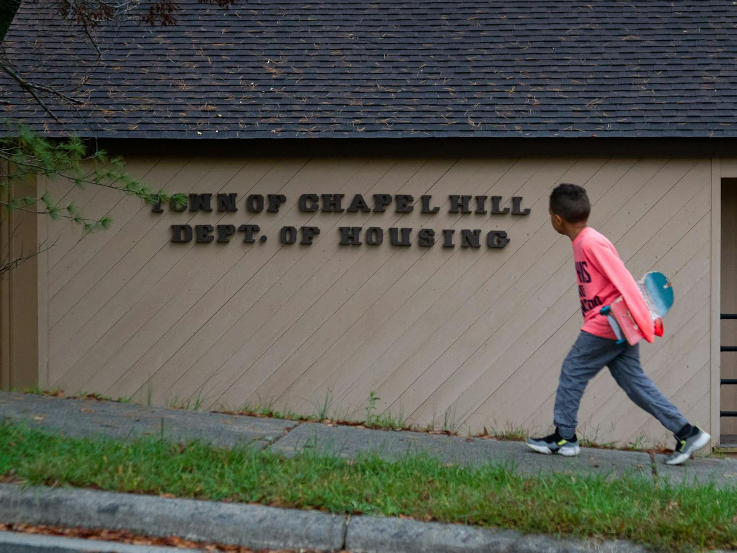 A young boy with a skateboard walks past the Chapel Hill Department of Housing in the Northside neighborhood of Chapel Hill on Sunday, Oct. 25, 2020.