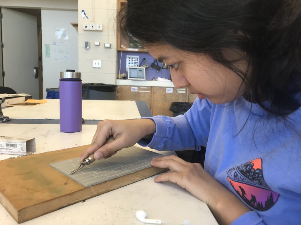 <p>Kylee Barrera, a student in ARTS 358: Letterpress, carves linoleum for her indulgence project on Wednesday, Feb. 26, 2020.&nbsp;</p>
