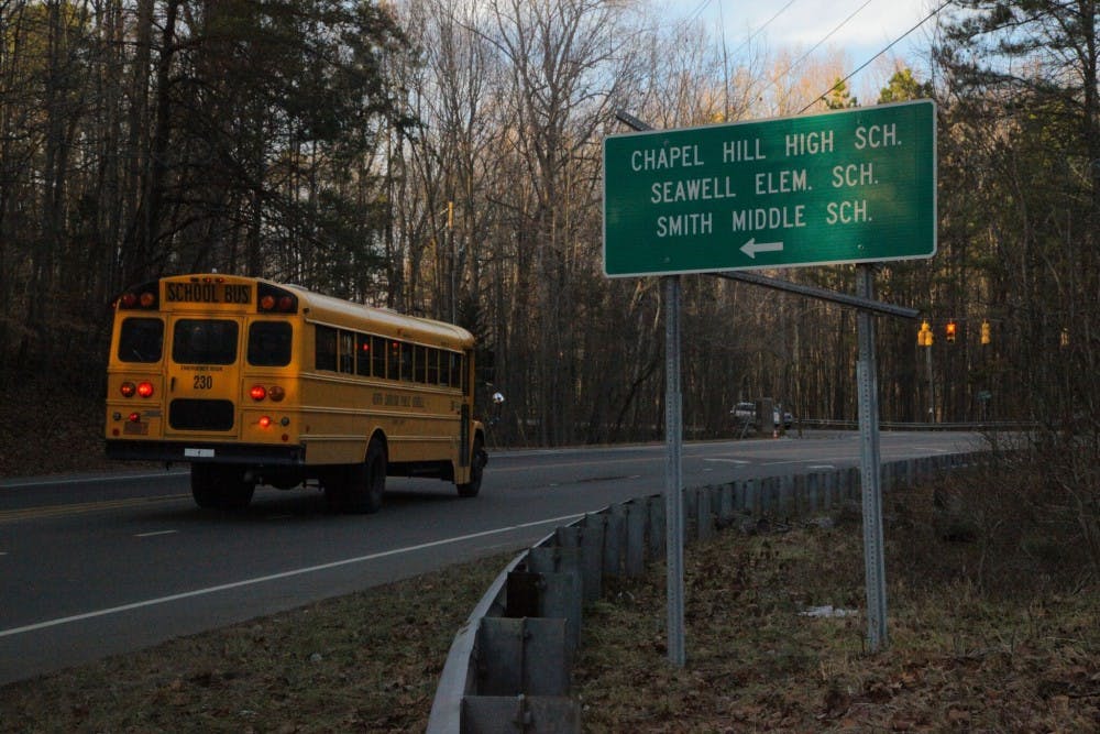 <p>A Chapel Hill-Carrboro City Schools bus drives toward Chapel Hill High School.</p>