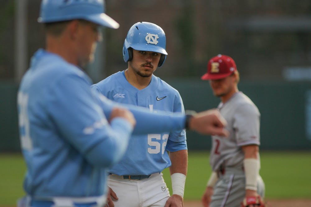 UNC sophomore catcher Tomas Frick (52) looks to head coach Forbes while on third base during the baseball game against Elon on Tuesday, Feb. 22, 2022, at Boshamer Stadium. UNC won 5-1.