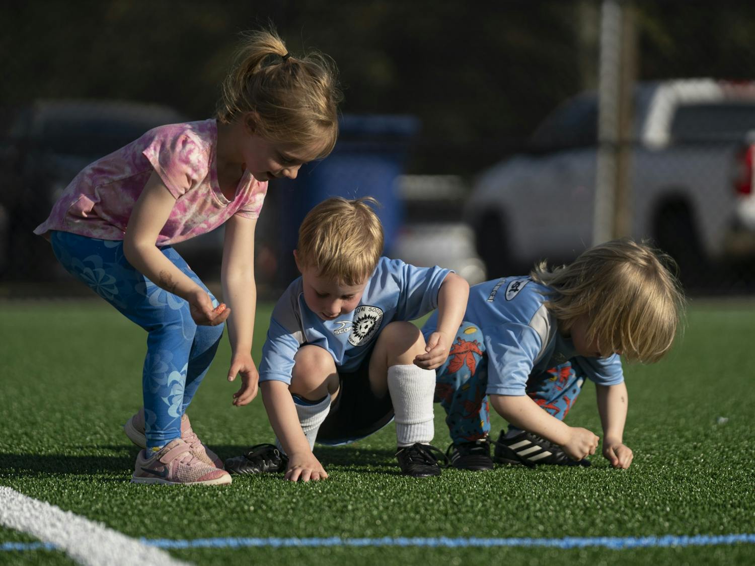 Young soccer players inspect and play with the new turf at Cedar Falls Park in Chapel Hill, N.C. on Thursday, Mar. 23, 2023. The Town of Chapel Hill held a ribbon-cutting ceremony to celebrate the freshly redone, environmentally-friendly turf for the multi-purpose field.