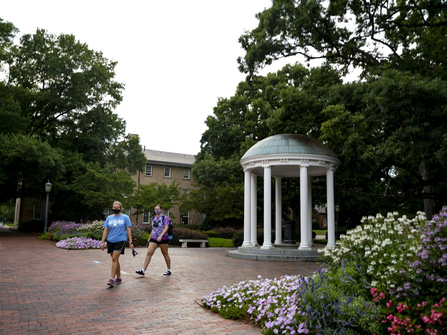 Students in masks walk past the old well on Friday, Aug. 14, 2020.
