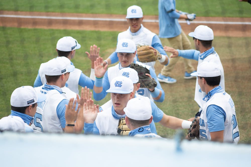 Tar Heel players get high fives from their teammates after a successful inning against University of Virginia at Boshamer Stadium on Saturday, Feb. 27, 2021. The Tar Heels won 2-1.