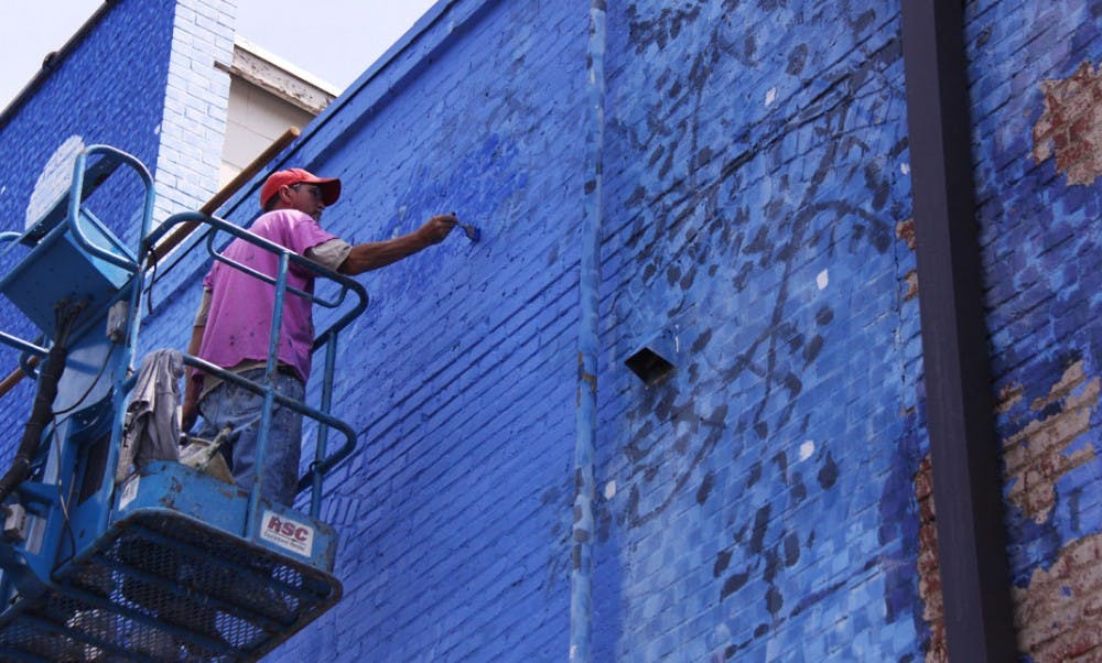 Chapel Hill artist Michael Brown restores “The Blue Mural,” which is located behind Starbucks Coffee on Franklin Street.