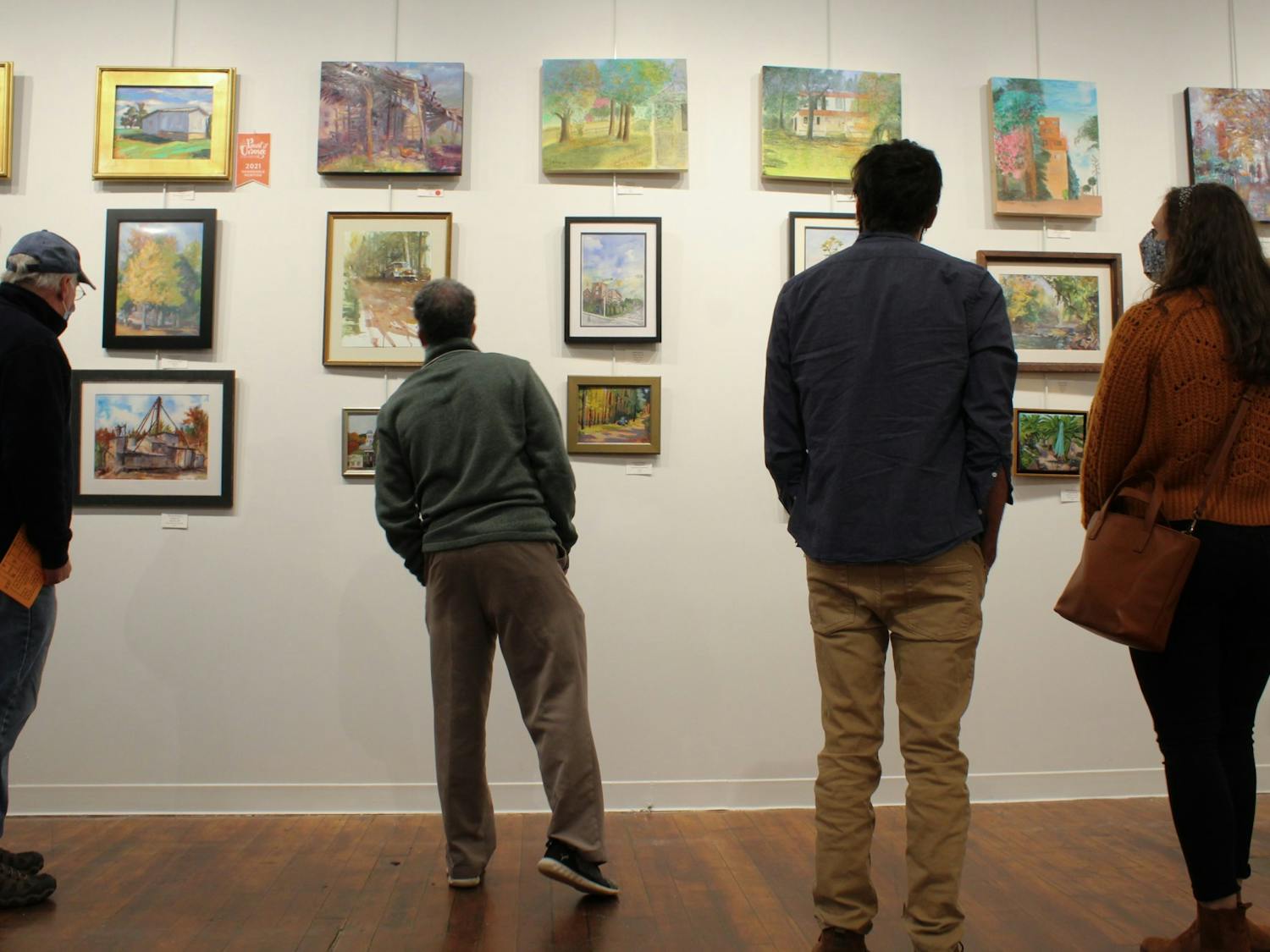 Artists and viewers admire paintings submitted to the 5th Annual Paint It Orange competition at the Eno Arts Mill in Hillsborough on Nov. 5.