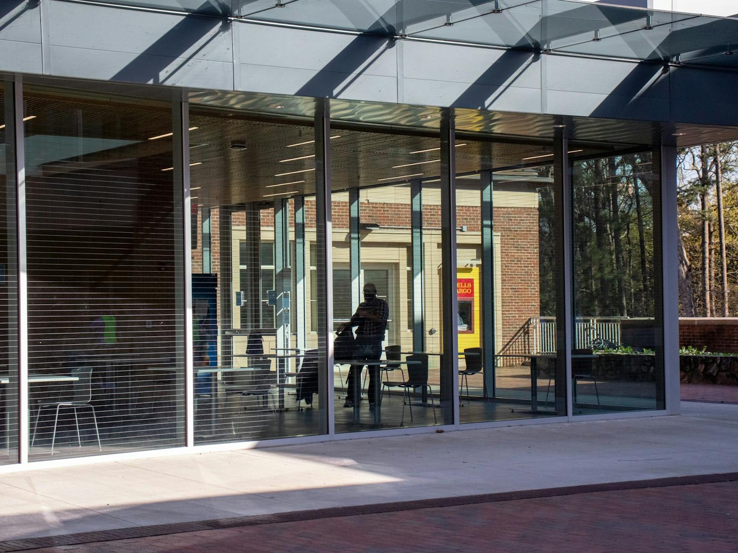 A student walks inside of glass extention to Chase Dining Hall on March 30, 2021.