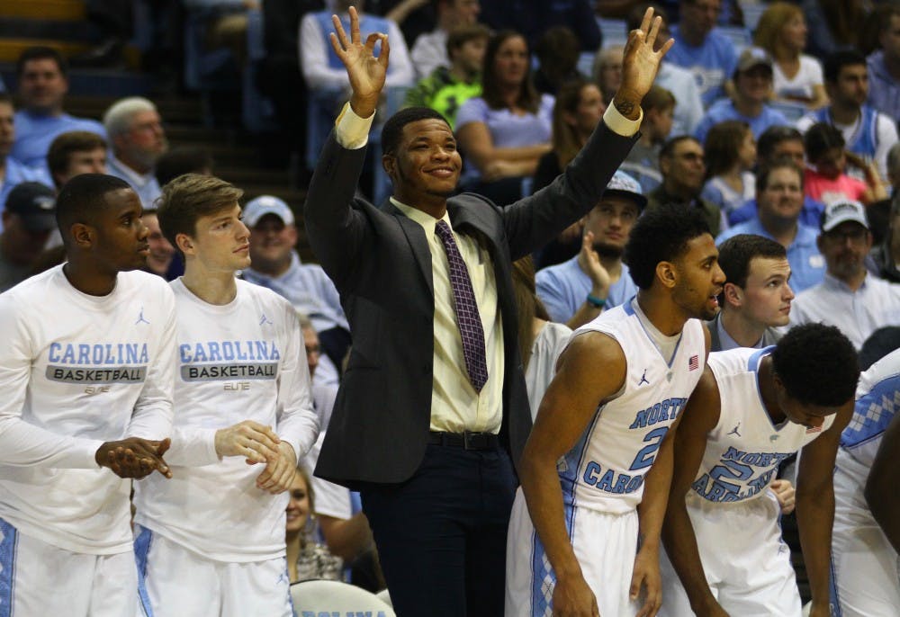 Kennedy Meeks celebrates a three-point shot by one of his teammates from the sidelines. 