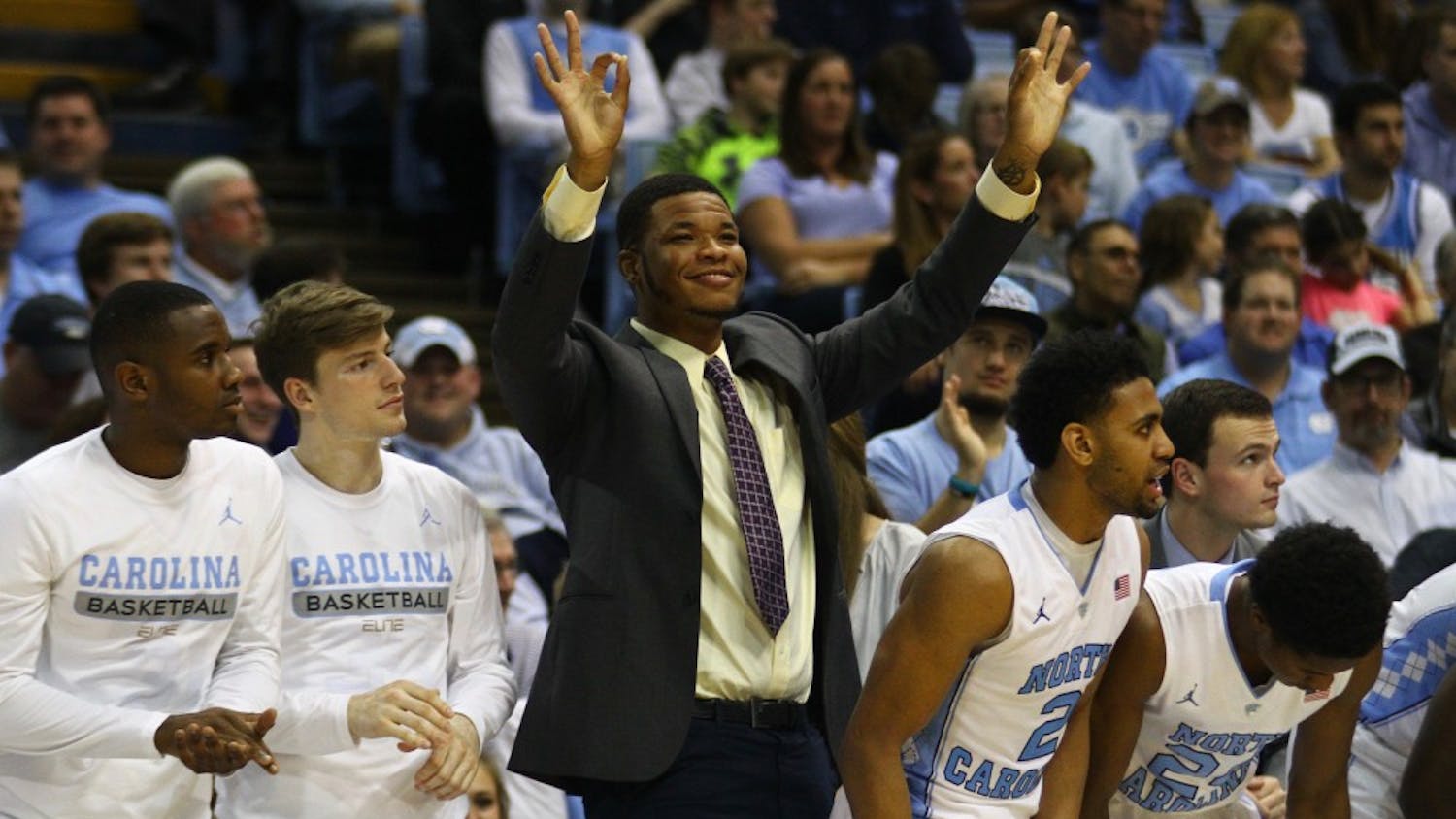 Kennedy Meeks celebrates a three-point shot by one of his teammates from the sidelines. 