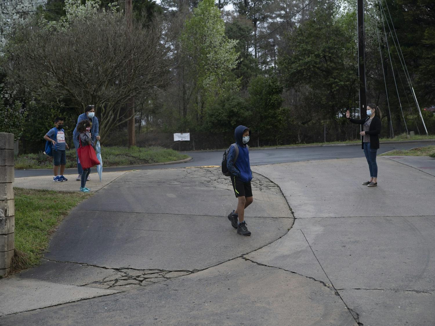 Students of Frank Porter Graham Elementary school walk from carpool toward the school early in the morning on March 26, 2021. CHCCS have recently reopened in-person instruction, although many children are still learning virtually.