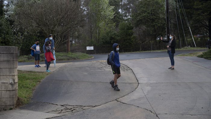Students of Frank Porter Graham Elementary school walk from carpool toward the school early in the morning on March 26, 2021. CHCCS have recently reopened in-person instruction, although many children are still learning virtually.