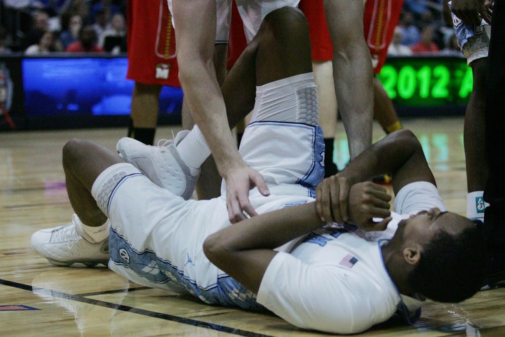 Junior John Henson grabs his wrist after getting injured early in the game. Henson spent most of the night on the bench tending to his wrist, seeing only 7 minutes of play time and scoring only 3 points for the night. 