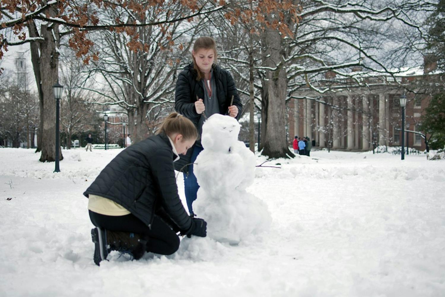 Freshmen Grace Baldridge and Emily Imes make a snowman on the quad on Thursday.