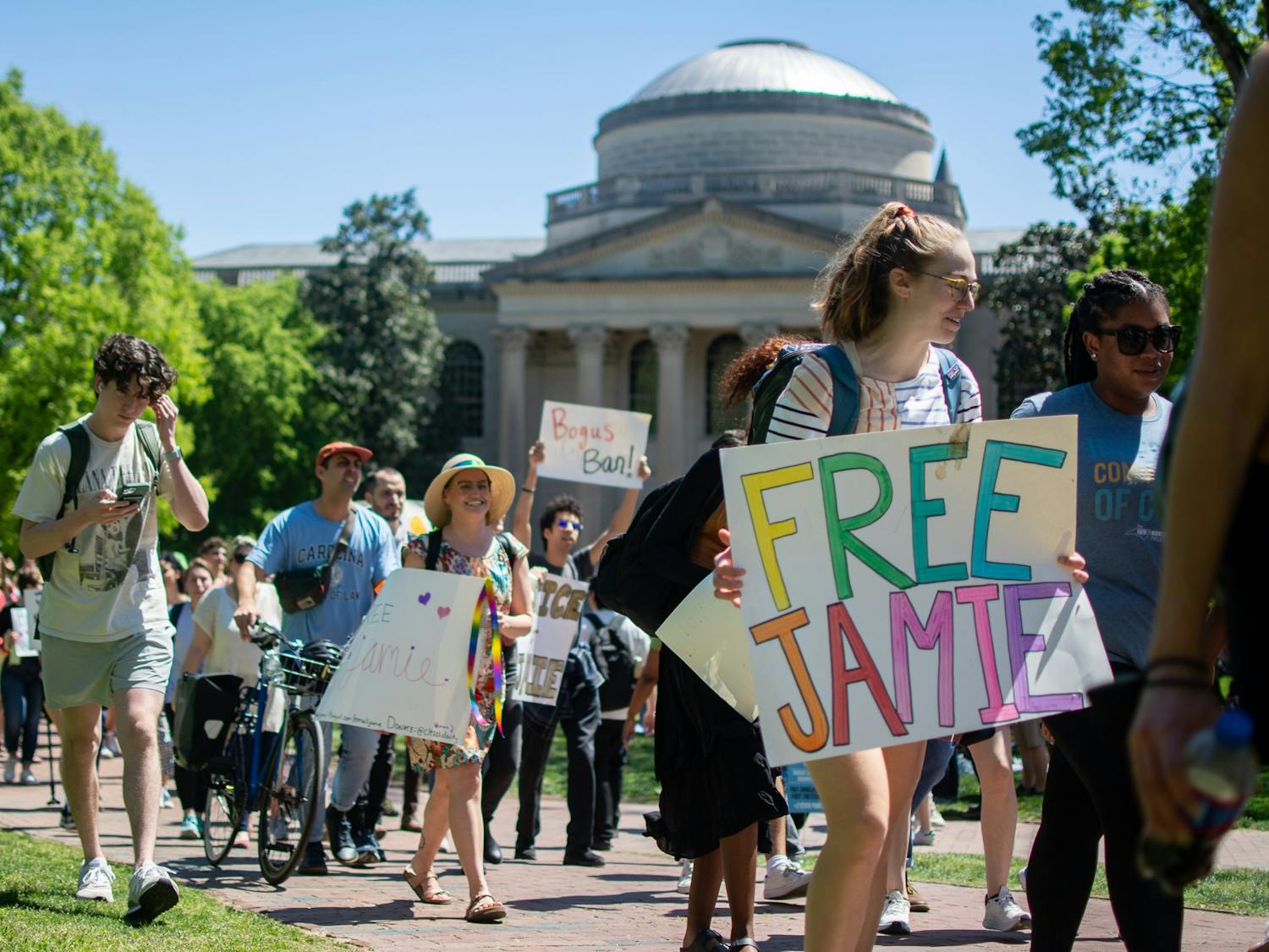 UNC Law students and other members of the campus community walk through Polk Place on Thursday, April 13. The students protested in support of Jamie Marsicano, a second-year law student barred from campus after their arrest in Georgia.