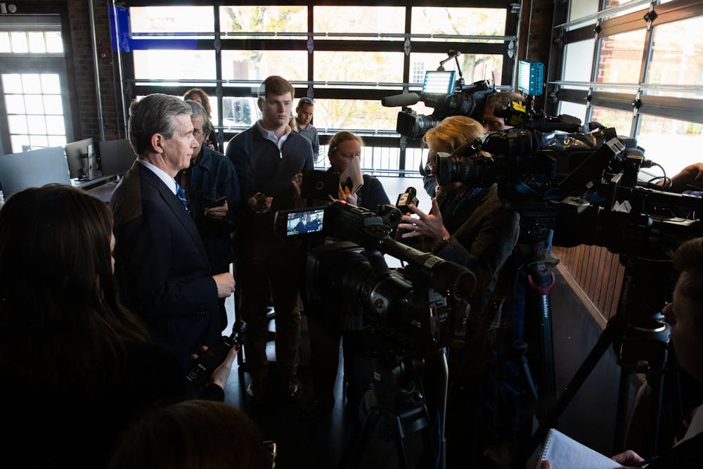 <p>Gov. Roy Cooper (left) stands for interviews following a press conference introducing Well Dot Inc., a health technology company, to the Chapel Hill area on Tuesday, Nov. 19, 2019. Well plans to create 400 new jobs.</p>