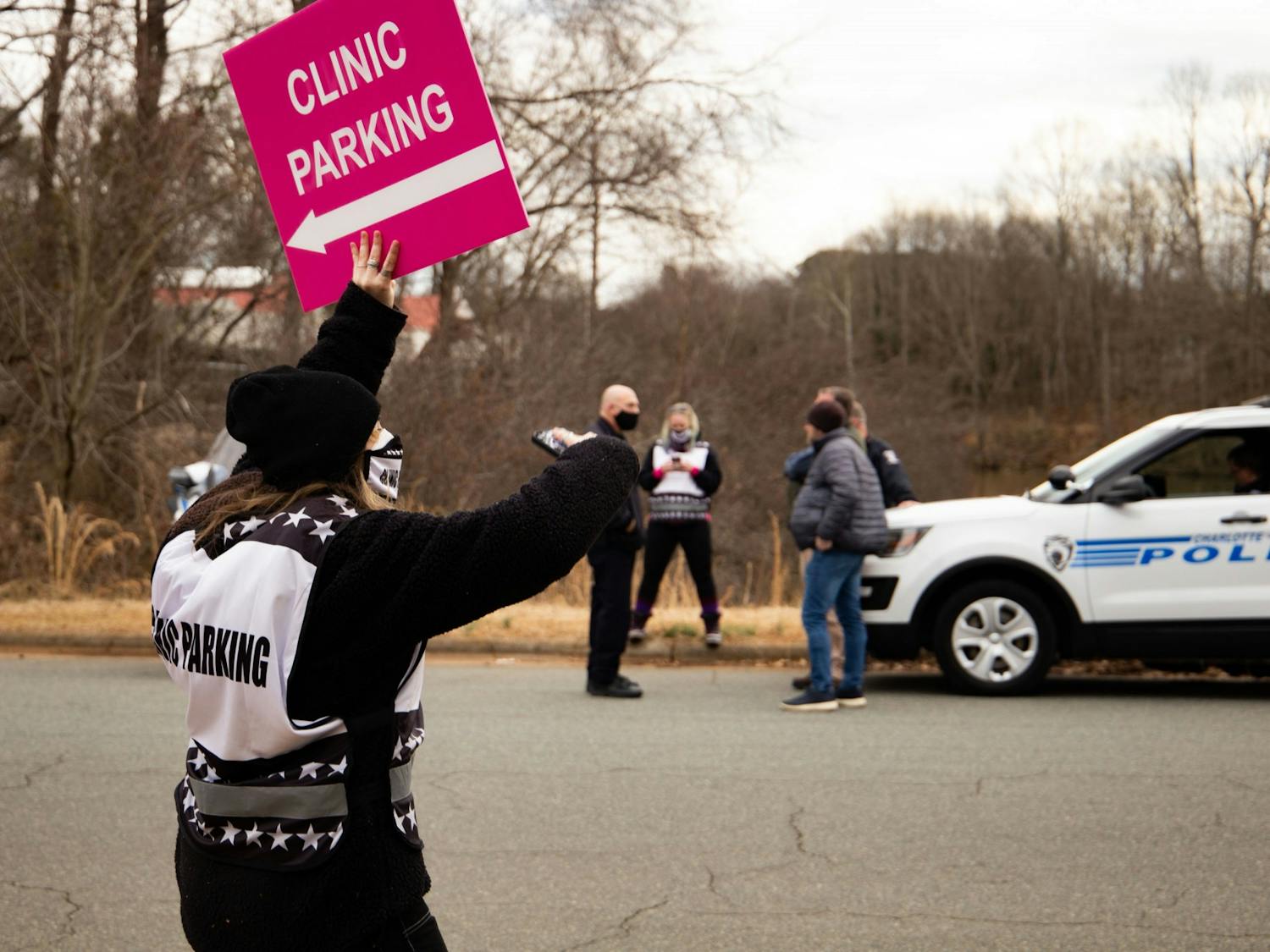 UNC student Reiley Baker directs vehicles towards the parking at A Preferred Women's Health Center of Charlotte while evangelical, anti-abortion activists argue with local police.