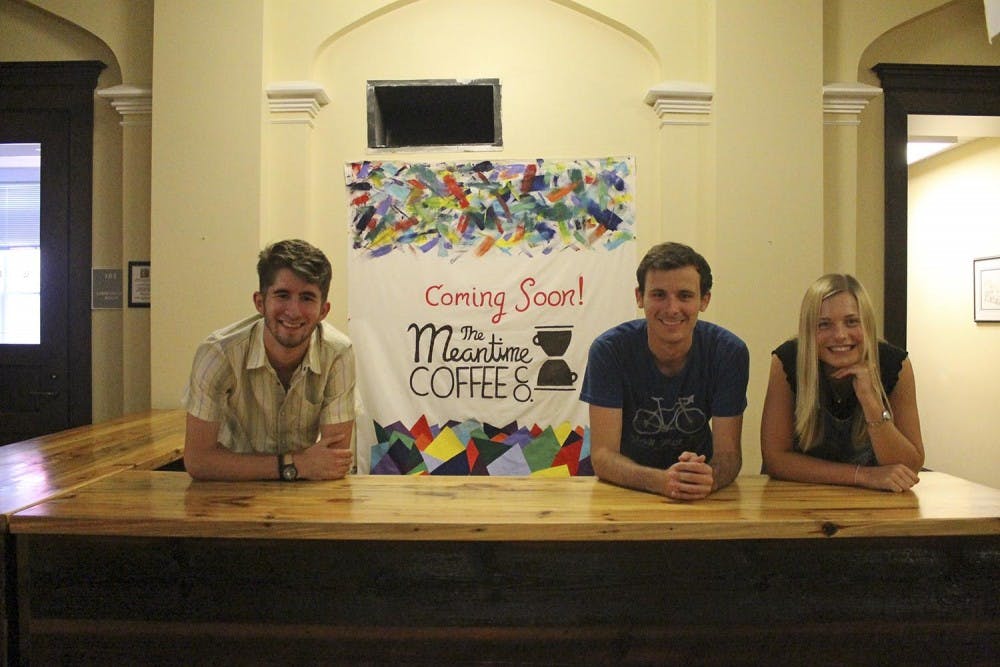 Scott Diekema (left), Keegan McBride and&nbsp;Lauren Eaves pose in front of the new sign for Meantime Coffee.&nbsp;
