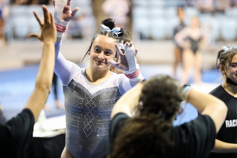 First-year Lali Dekanoidze celebrates with her teammates after a 9.825 performance on bars during UNC gymnastics' home meet at Carmichael Arena on Friday, Jan. 28, 2022.