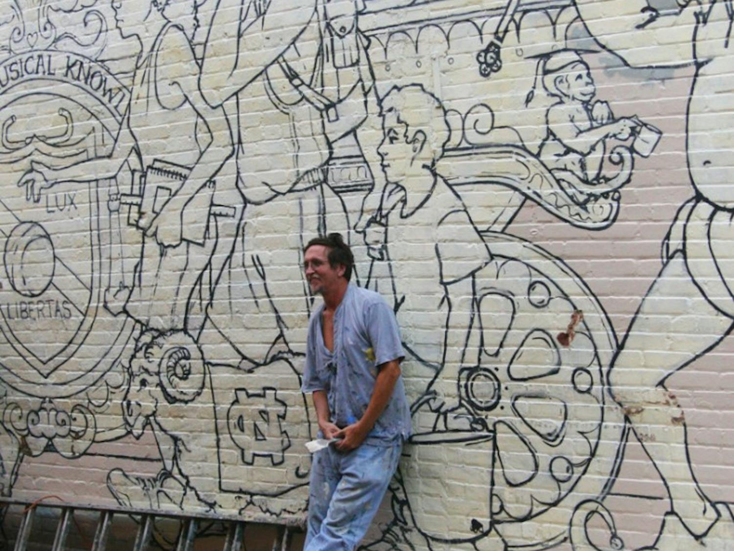 Artist Michael Brown repaints a mural in Porthole Alley off of Franklin Street during the afternoon of Sept. 21. The mural is funded by UNC and the Chapel Hill Preservation Society. 