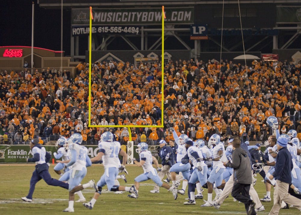 	UNC players rush the field after Casey Barth&#8217;s field goal puts the Tar Heels up 30-27 for the win.