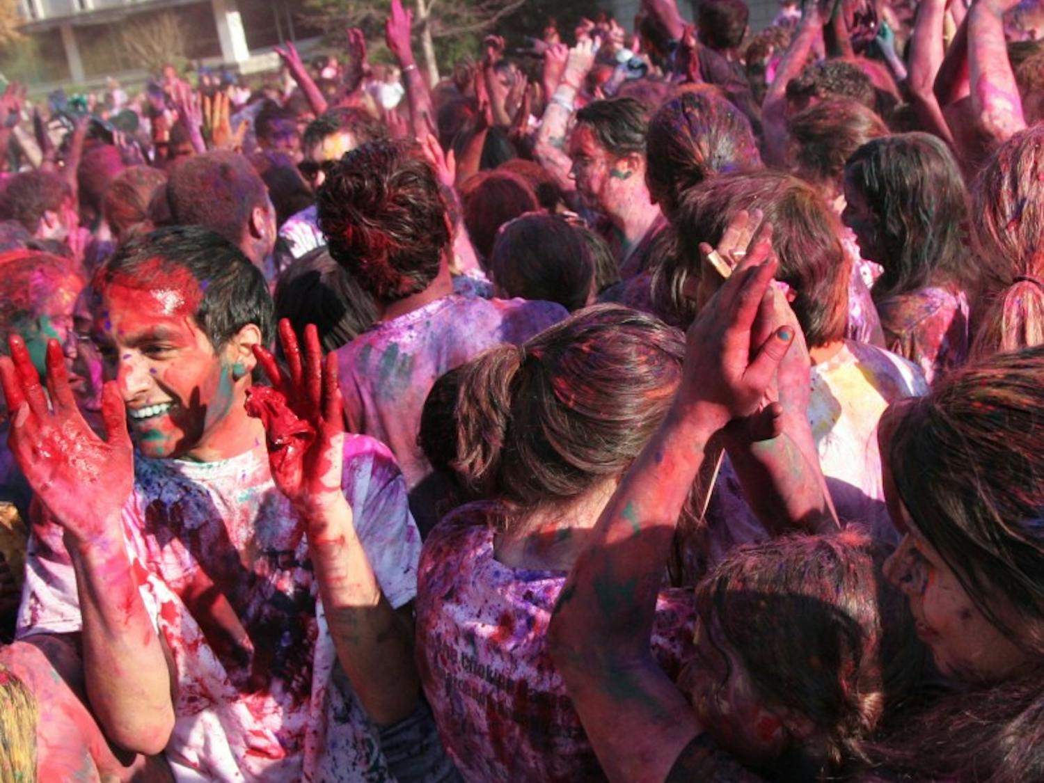 Students throw paint during UNC's Holi celebration Friday afternoon.