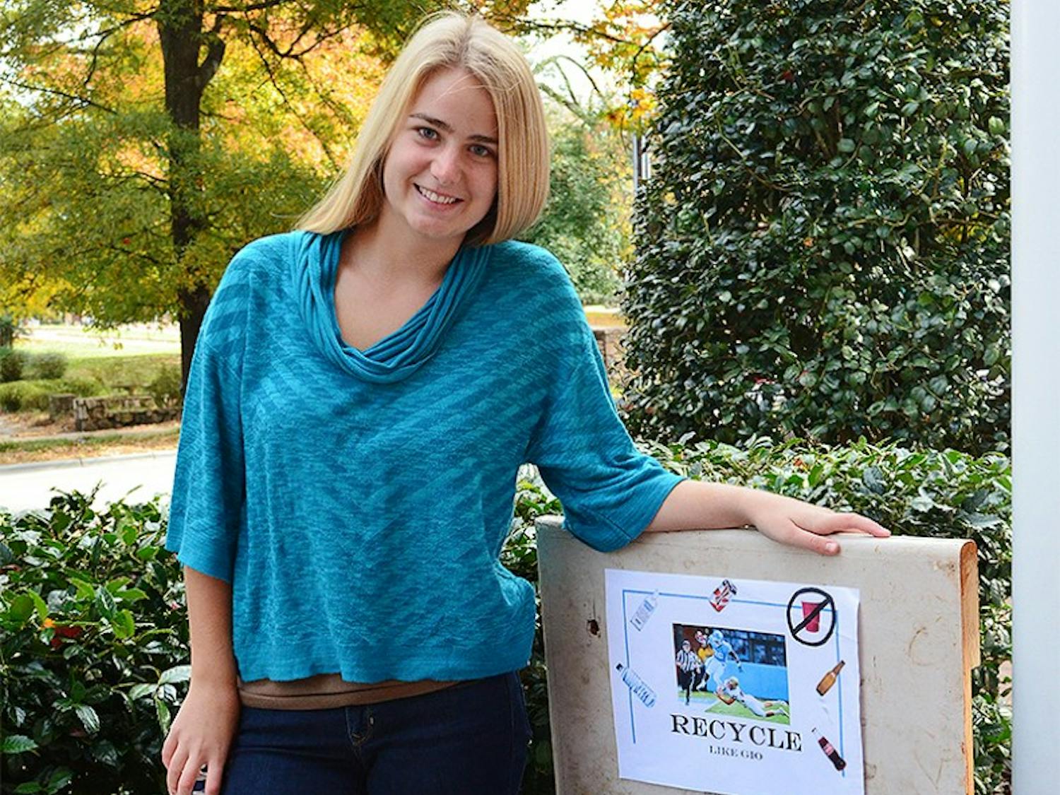 Elly Withers stands with one of the recycling bins she has altered in order to make recycling more fun. She hopes to encourage all of the fraternities on campus to join in with her recycling campaign. 