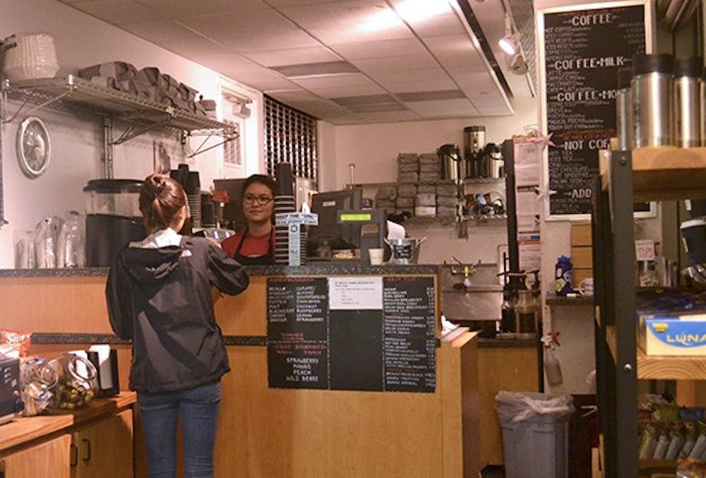 <p>Stephanie Kim, a sophomore student, buys coffee from barista Mariko Davison at the Daily Grind located in the student store.</p>
