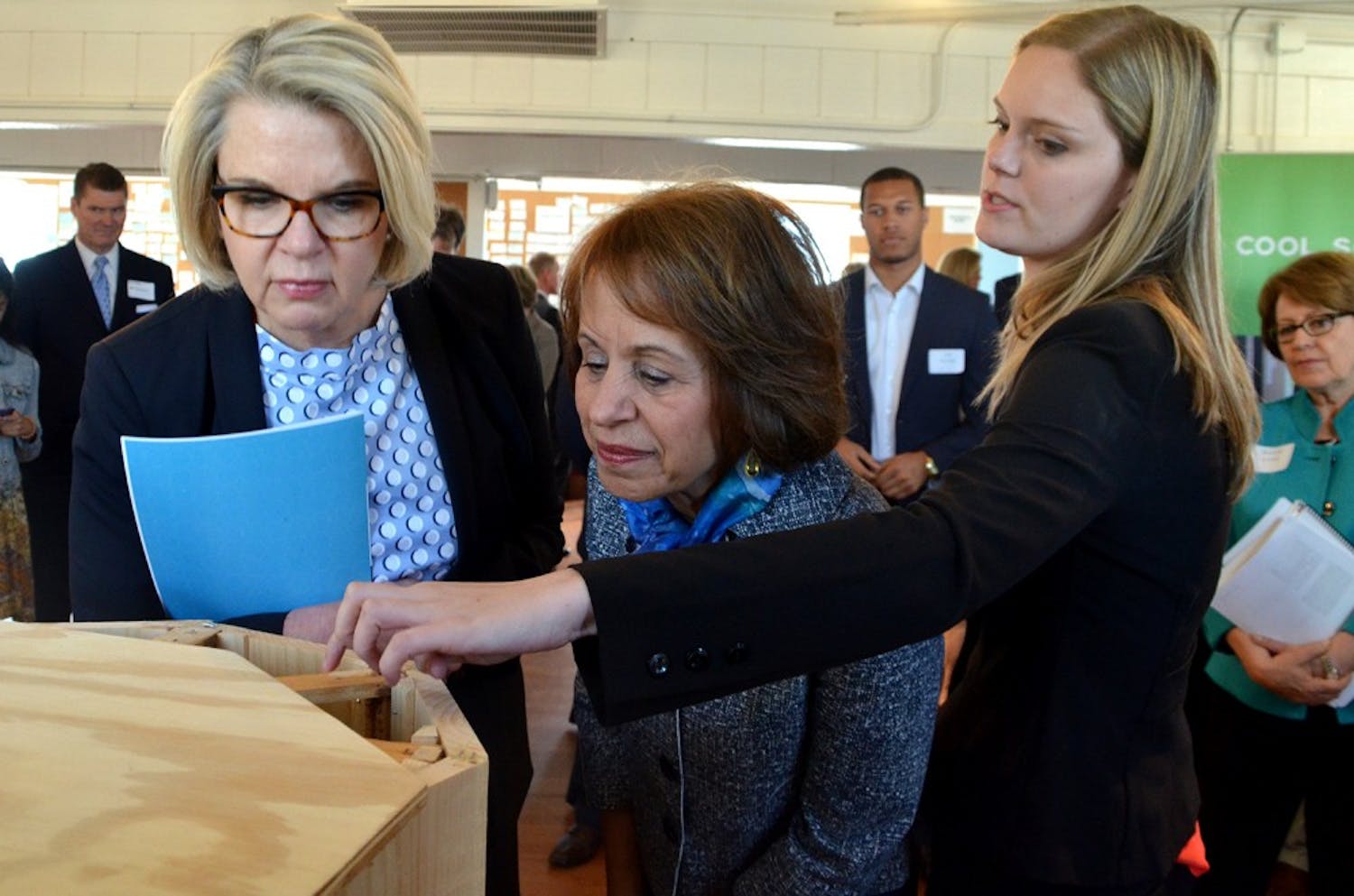 Alsey Davidson shows UNC System President Margaret Spellings and Chancellor Carol Folt how Honey Halo's beehive design can save the lives of honeybees.