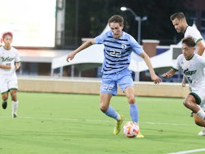 UNC graduate midfielder Milo Garvanian (22) dribbles the ball past defenders during a home game against South Florida at Dorrance Field on Aug. 28, 2022.