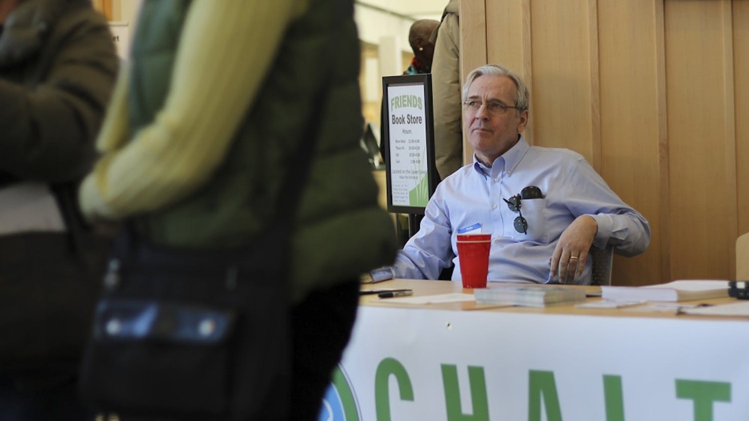 Chapel Hill Alliance for a Livable Town (CHALT) member Don Evans sits behind the organization's informational booth in CH Public Library during their public forum meeting on Sunday.