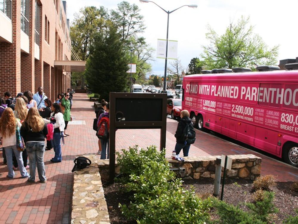 Students gather for photographs with Planned Parenthood's large pink bus and interest forms outside of the Student Union on South Road. Planned Parenthood met with UNC's chapter of VOX after a brief delay due to the morning's multiple traffic issues.
