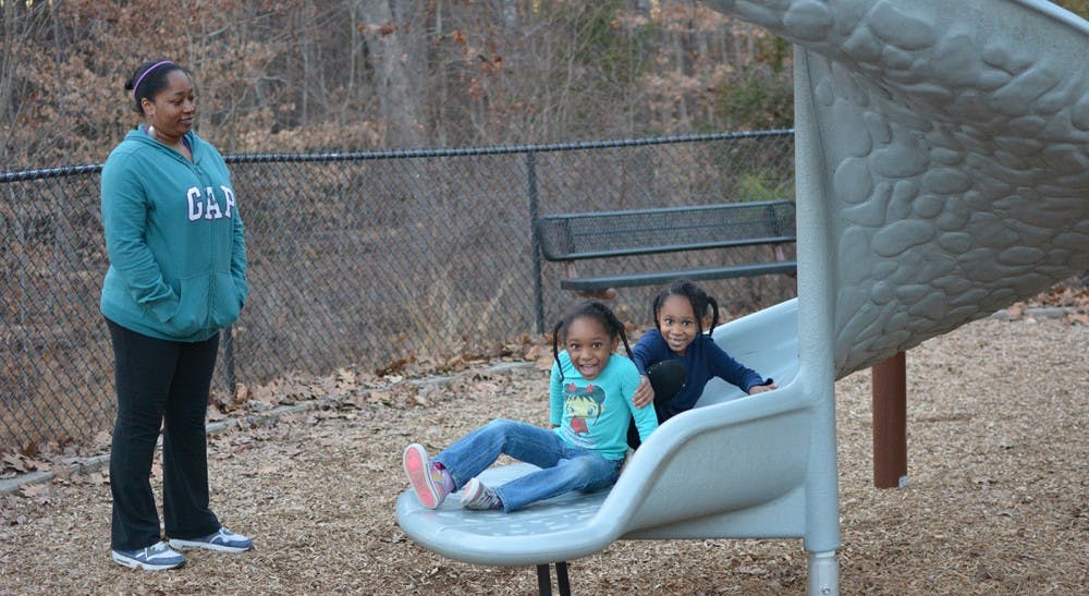 Shantina Foster watches her daughters Catherine Thorpe (in navy) and Kaelyn Thorpe (in light blue) play at Hank Anderson Park in Carrboro.