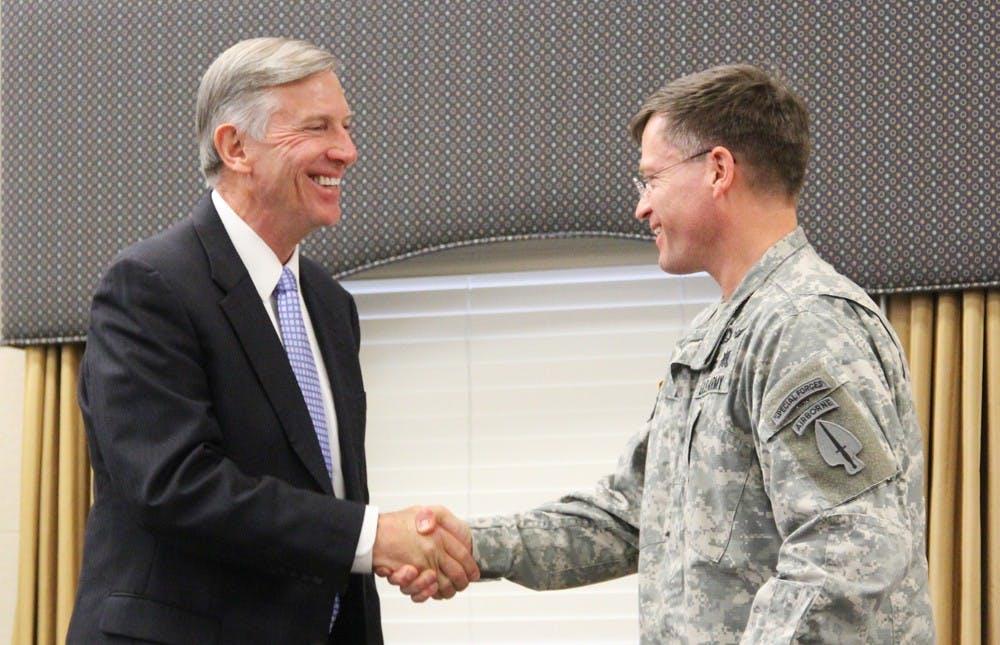 UNC president Thomas Ross and Col. Peter Benson shake hands as they exchange coins in honor of military tradition and of the new health care effort.