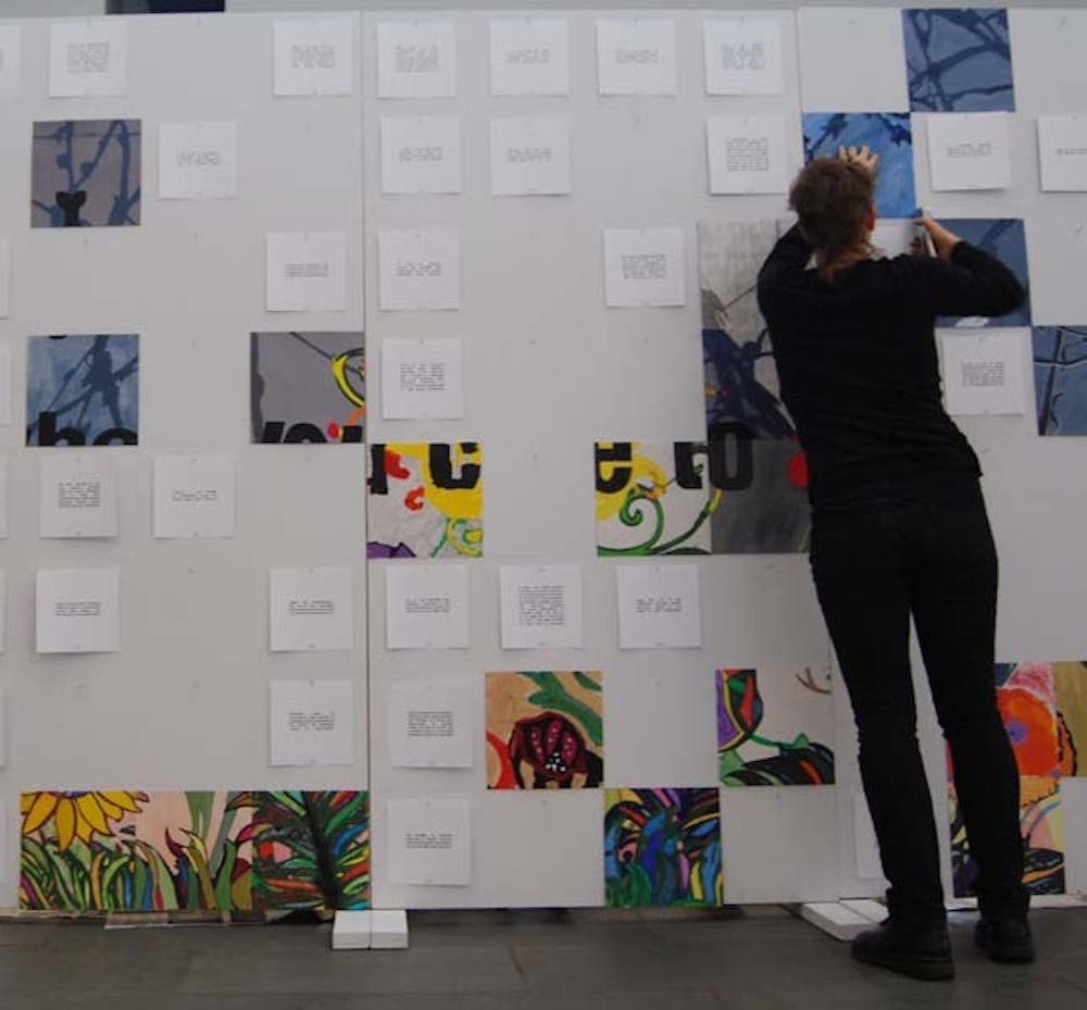 Peter Pendergrass, a senior from Greensboro, puts a clip on the Collaborative Art Wall at the FedEx Global Education Center on Saturday.