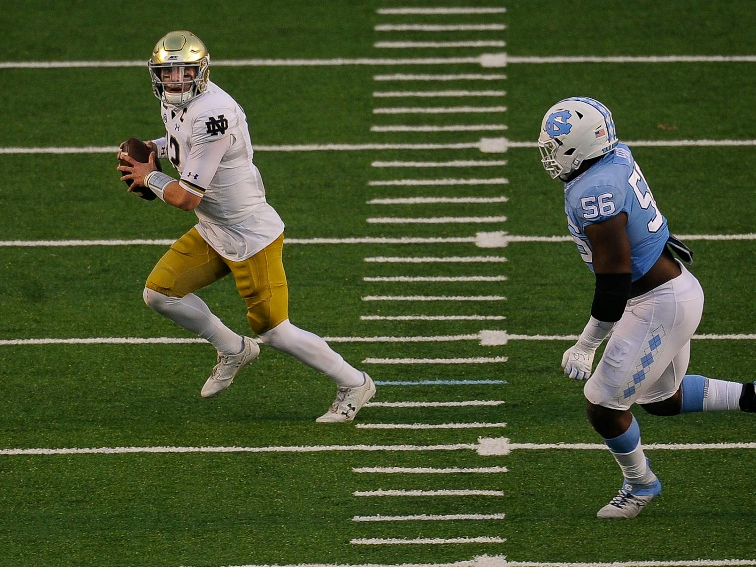 Notre Dame's graduate quarterback Ian Book (12) runs the ball downfield in Kenan Memorial Stadium during a game against UNC on Friday, Nov. 27, 2020. 