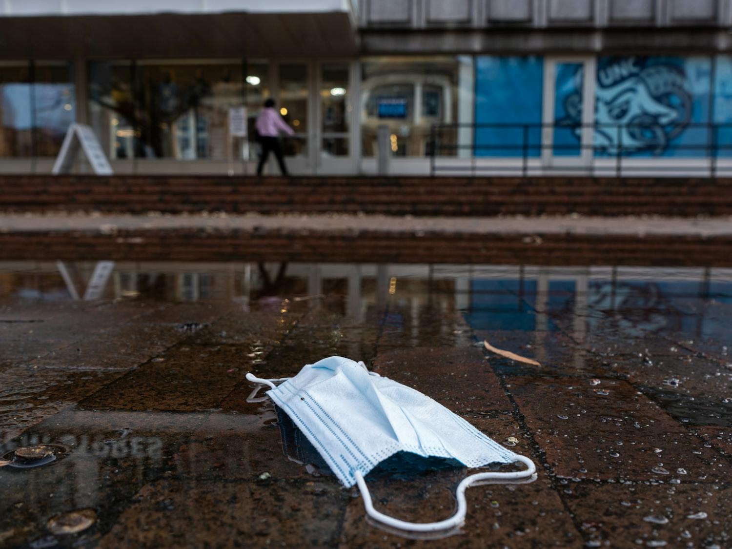 A mask lies in a puddle in front of the Student Stores Building in January.