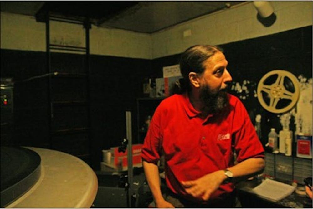 Stuart Hoyle, projectionist at the Varsity Theater, explaining how the reels are fed into the device. DTH/Jordan Lawrence