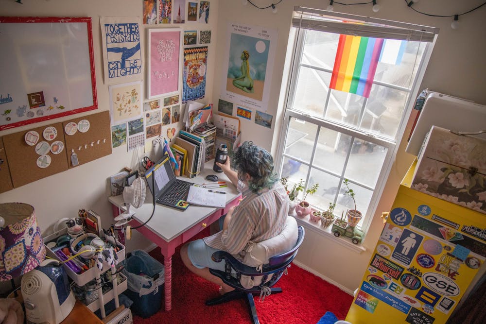 <p>Sophomore SamLevi Sizemore completes his German homework in his Chapel Hill apartment on Thursday, Sept. 10, 2020. As a studio art and English double major, Sizemore has filled his workspace with posters, plants and flags to make his apartment feel like home.</p>