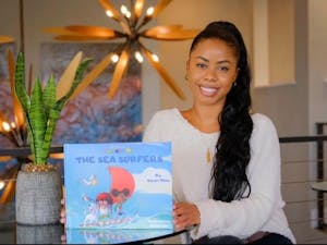 Sakari Milan, UNC alumna and author, with her book The Tales of Camelia B.: The Sea Surfers. Photo courtesy of Milan.
