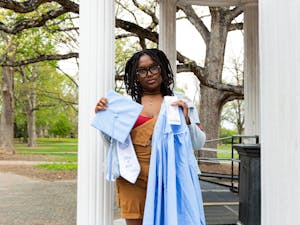 Treasure Rouse, a graduating senior, stands at the Old Well while holding her graduation cap, gown, stole and receipt on March 30, 2023. The total cost of everything was $112.65.