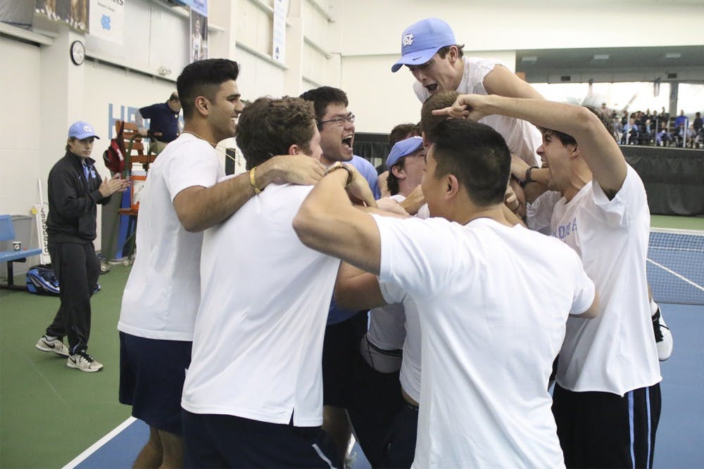 No. 7 UNC Men's Tennis team mobs senior Brett Clark after he won his match in three sets to secure the team's victory over No.5 Oklahoma 4-3 Sunday afternoon.